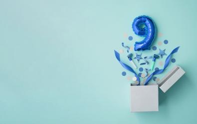 a number 9 balloon popping out of a box with streamers