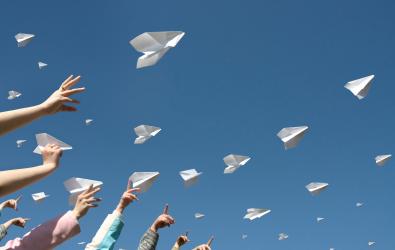 people holding paper airplanes to the sky