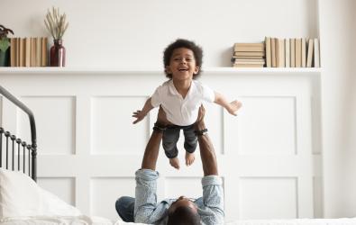 child playing flying on dads arms