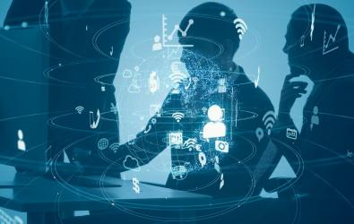 Silhouette of workers around a monitor with digital icons around them.