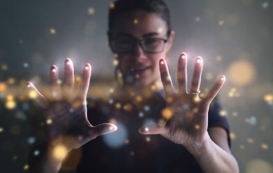 Woman holding up hands with points of light.