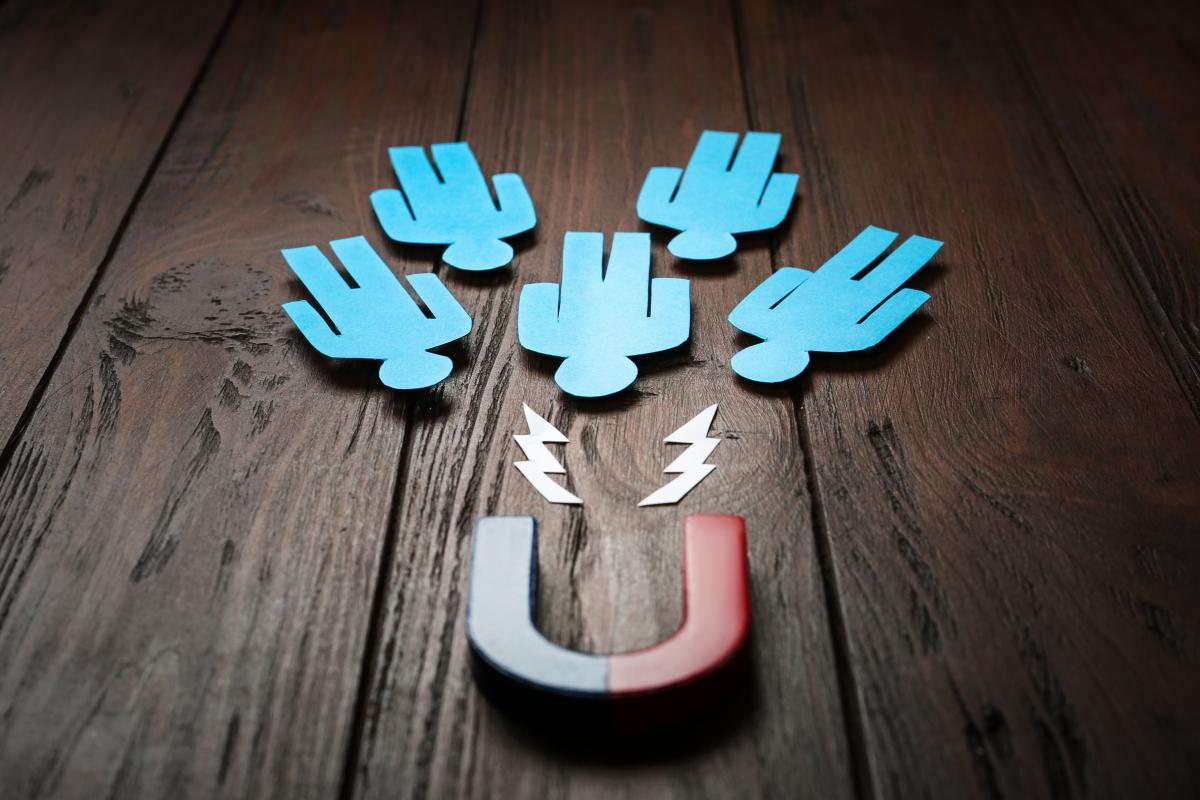 blue paper cutouts of people being drawn to a magnet