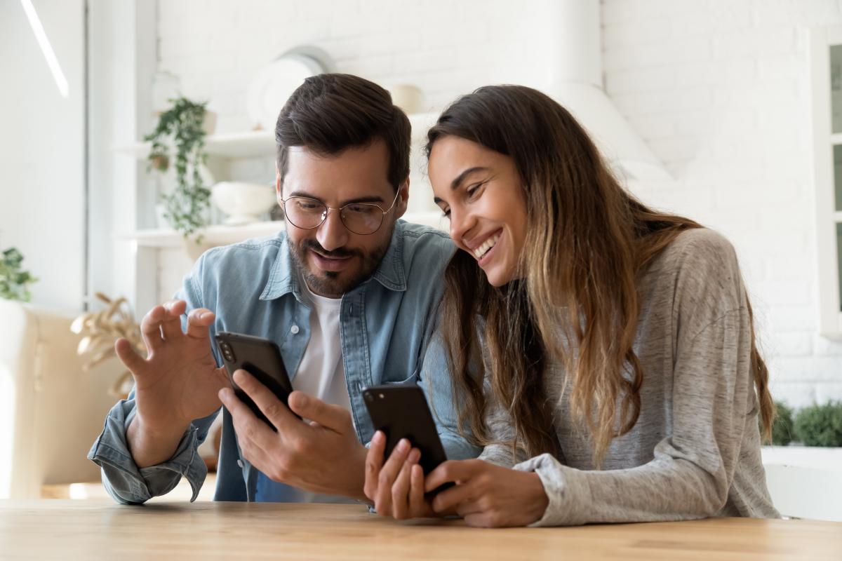 Man and woman smiling and looking at smartphones