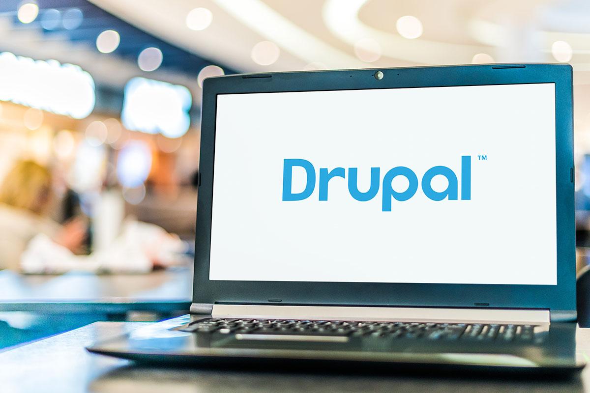 Laptop with Drupal logo placed on a desk in an office.