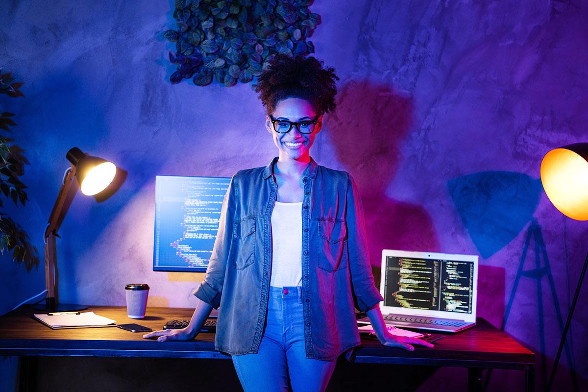 Woman with glasses standing in front of computers.