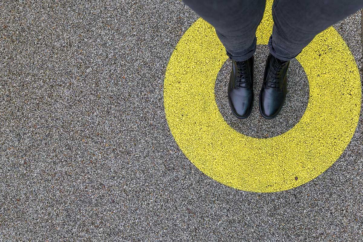 Person in black shoes standing within a circle.